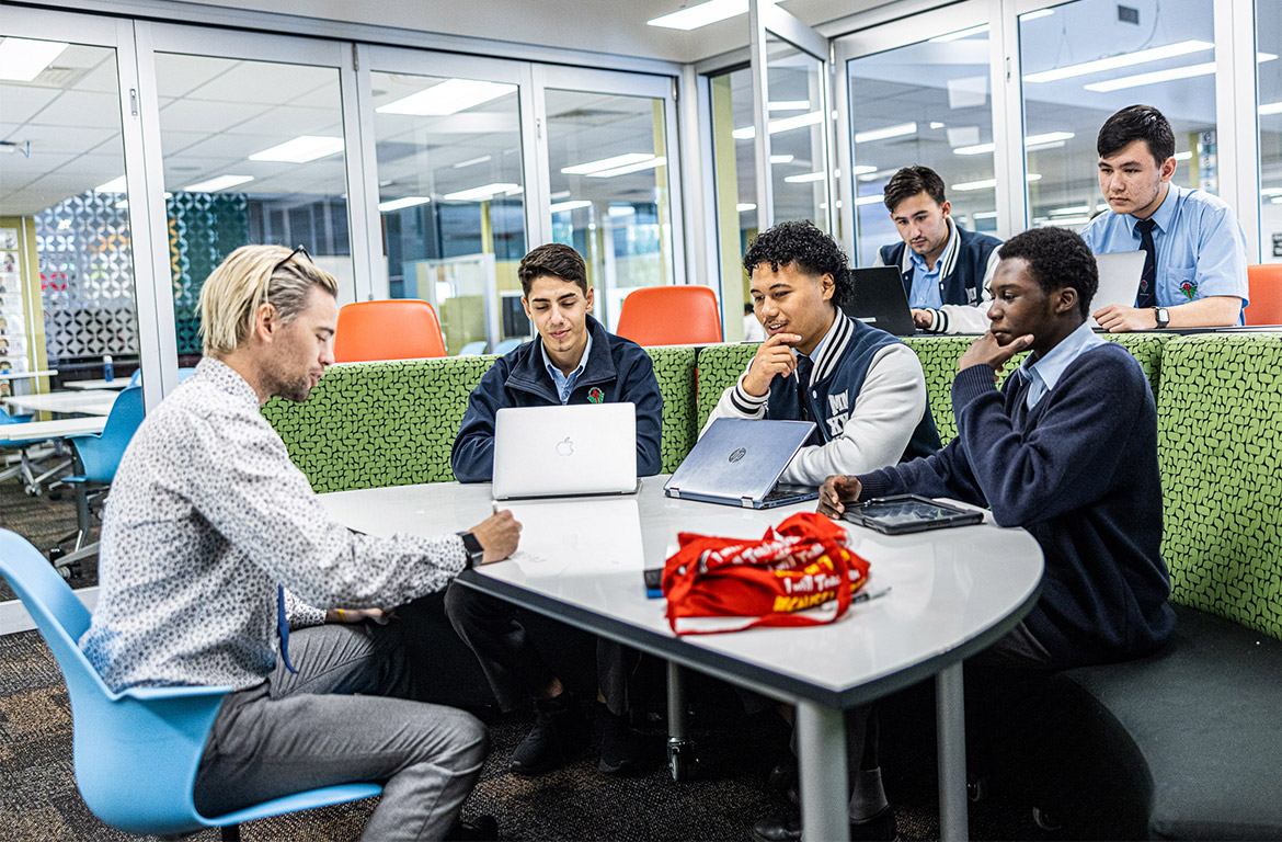 Teacher with senior students at Delany Catholic College Granville