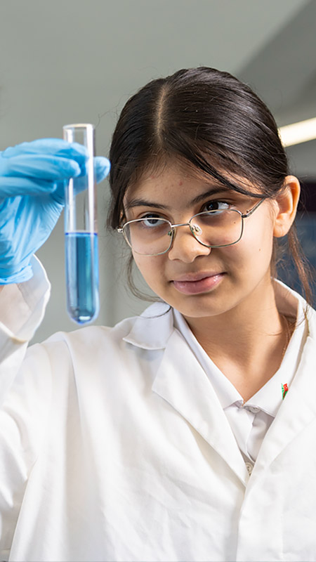 Delany College Granville science student holding a test tube full of blue liquid.