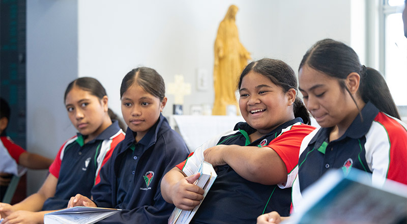 Delany Granville students in class, a statue of Jesus in the background