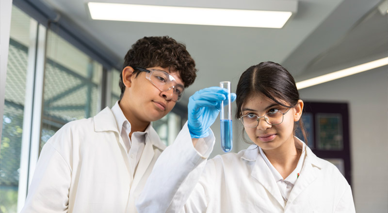 Science Class at Delany Granville, students in labcoats holding up vial